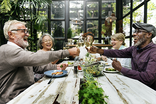 mature adults toasting a dinner table