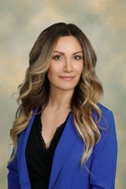 Portrait of Kristen Duppstadt wearing a black shirt and blue blazer.