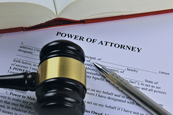 An image of a gavel and pen laying on top of Power of Attorney forms.